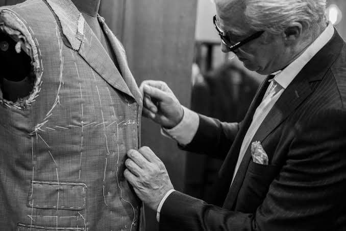 Sastre ajustando un saco hilvanado sobre un maniquí